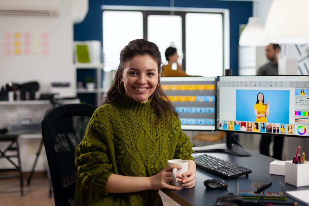 Woman retoucher looking at camera smiling working in creative media agency